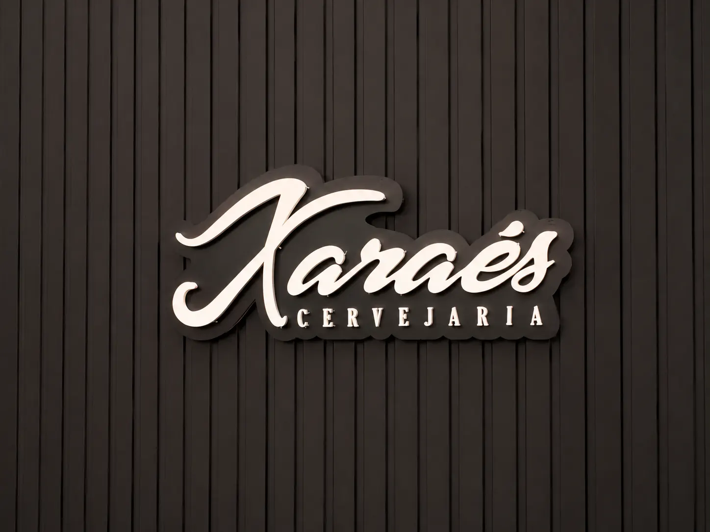 Letreiro iluminado Karaés Cervejaria sobre painel escuro